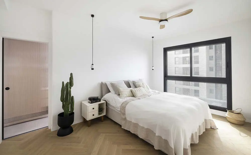 חדר שינה הורים מרווח ומעוצב, הכולל מיטה זוגית גדולה עם טקסטיל עשיר וארון קיר מותאם אישית שיוצר מראה אלגנטי ופתרון אחסון יעיל.