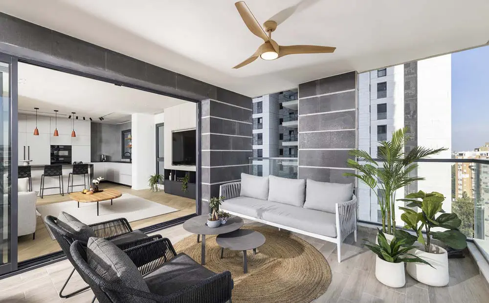 מבט פנורמי מהמרפסת, המציג עיצוב פנים יוקרתי של הדירה ואת הנוף האורבני המרהיב הנשקף מהקומה ה-13, הכולל את קו הרקיע של העיר.