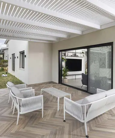 רחבת יציאה לגינה עם ריצוף פישבון ופרגולה מעץ