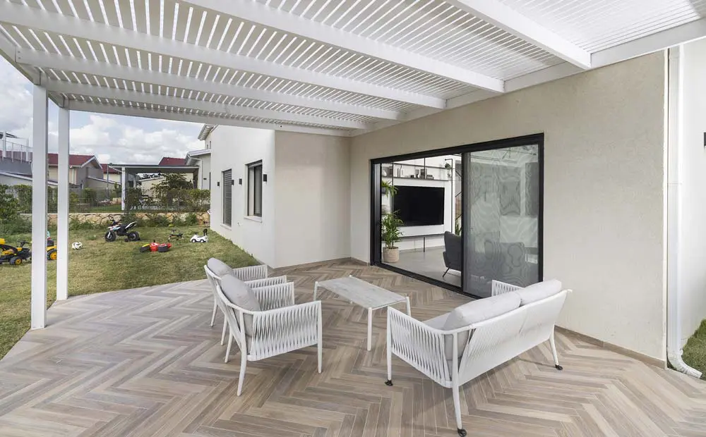 רחבת יציאה לגינה עם ריצוף פישבון ופרגולה מעץ