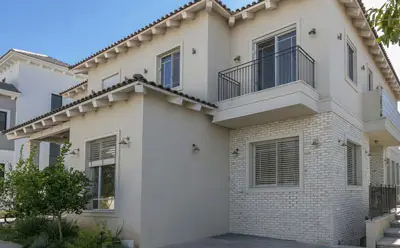 חזית בית פרטי כפרי עם חיפוי בריקים בהירים ומדרגות בטון