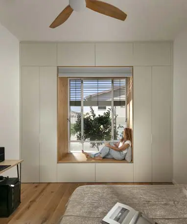 נישת חלון מעץ בתוך קיר ארונות אינטגרלי בחדר שינה עם רצפת עץ טבעי