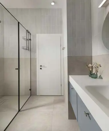 חדר אמבטיה כללי עם מקלחון זכוכית, כיור אינטגרלי וארון בגוון תכלת בהיר