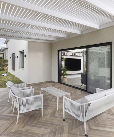 רחבת יציאה לגינה עם ריצוף פישבון ופרגולה מעץ